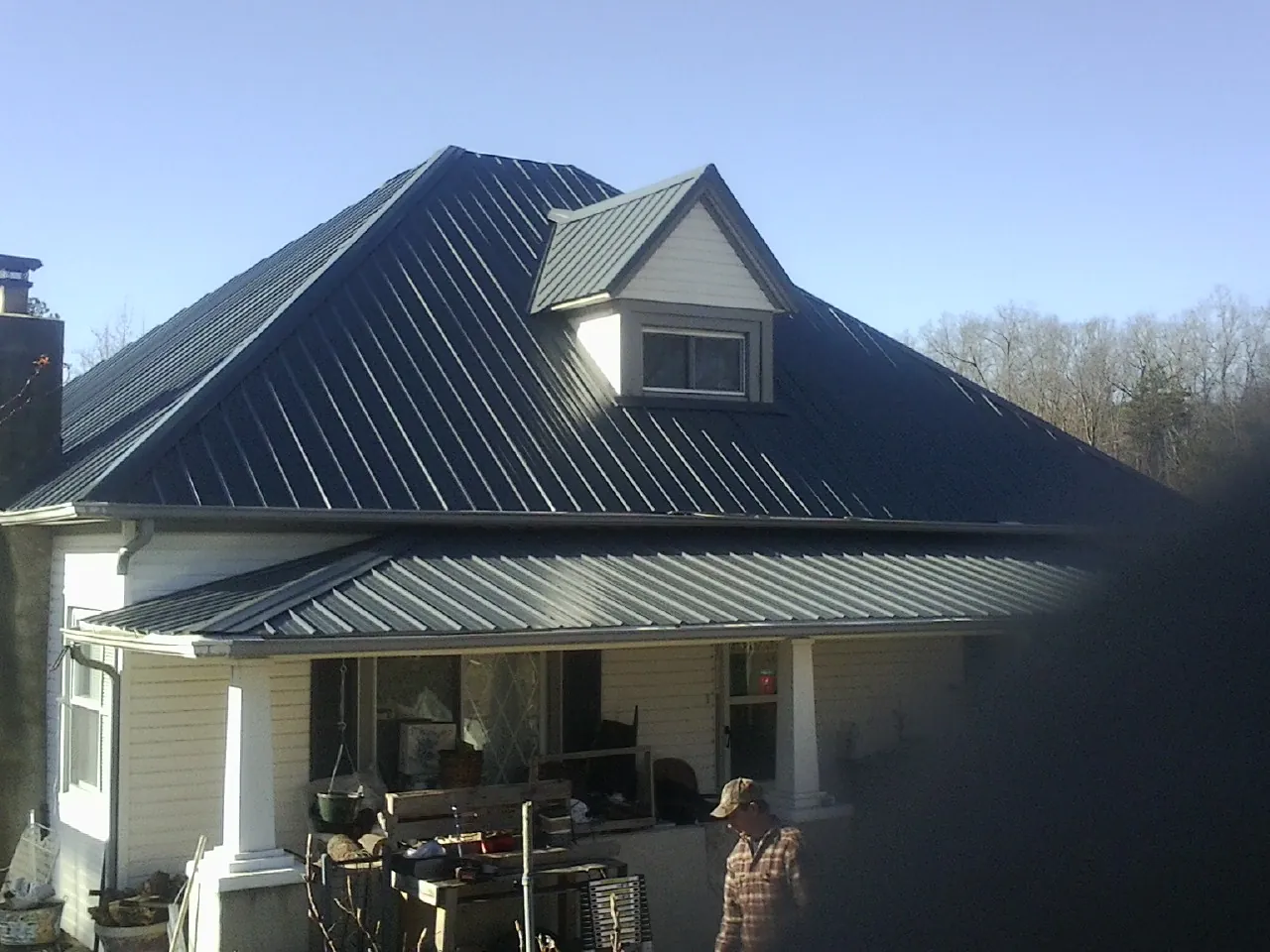 Dark blue standing seam metal roof with a dormer above a front porch in Pantego