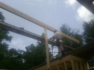 Carpenter setting a ridge beam over a new addition frame — Ice Dam Removal by Roofing Brothers in Pantego