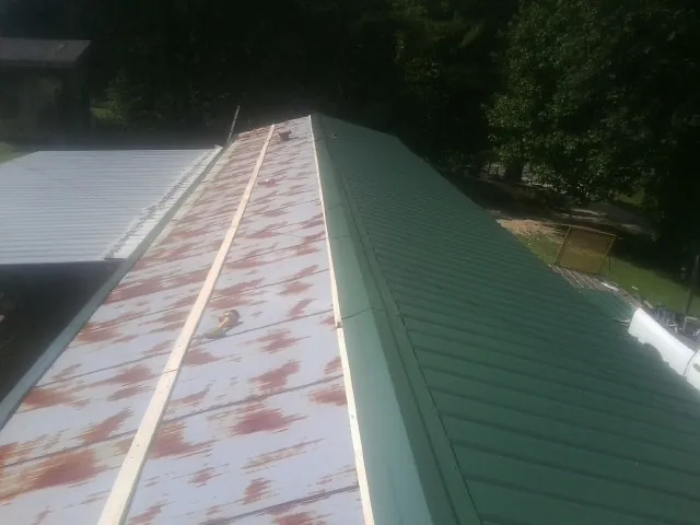 Old rusted panels beside newly installed green metal roofing — Wind Damage Roof Repair by Roofing Brothers in Pantego