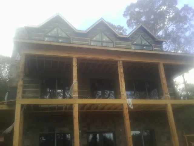 Dormers and porch framing on a large log home under construction — Roof Coating work by our crew in Pantego
