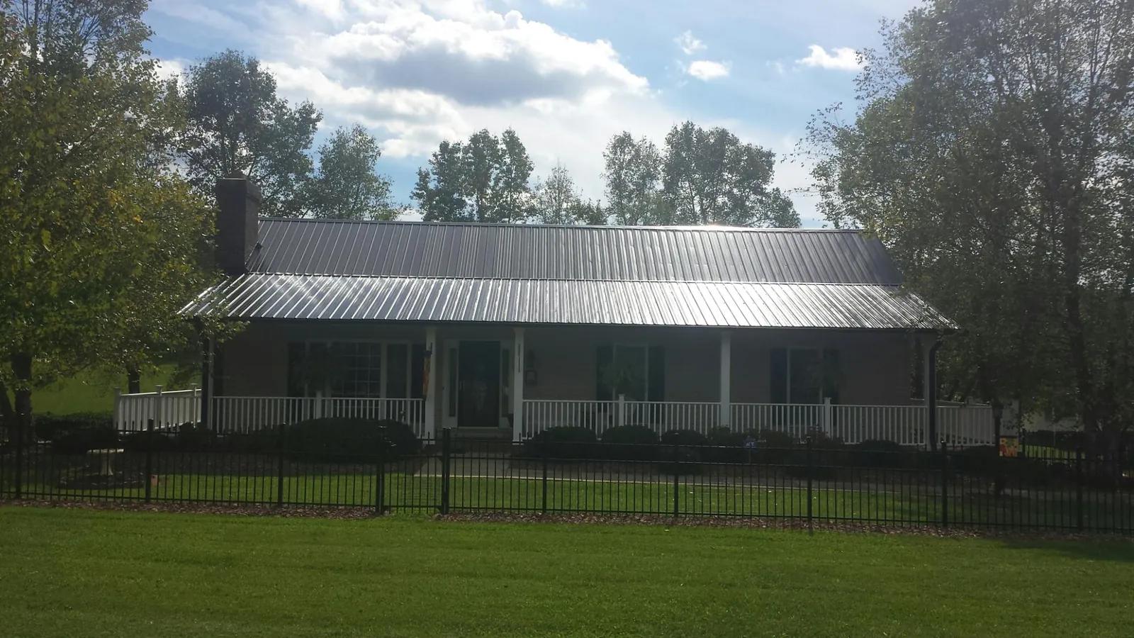 Gray metal roof on a brick ranch with a full width front porch — Gutter Guard Installation work by our crew in Pantego