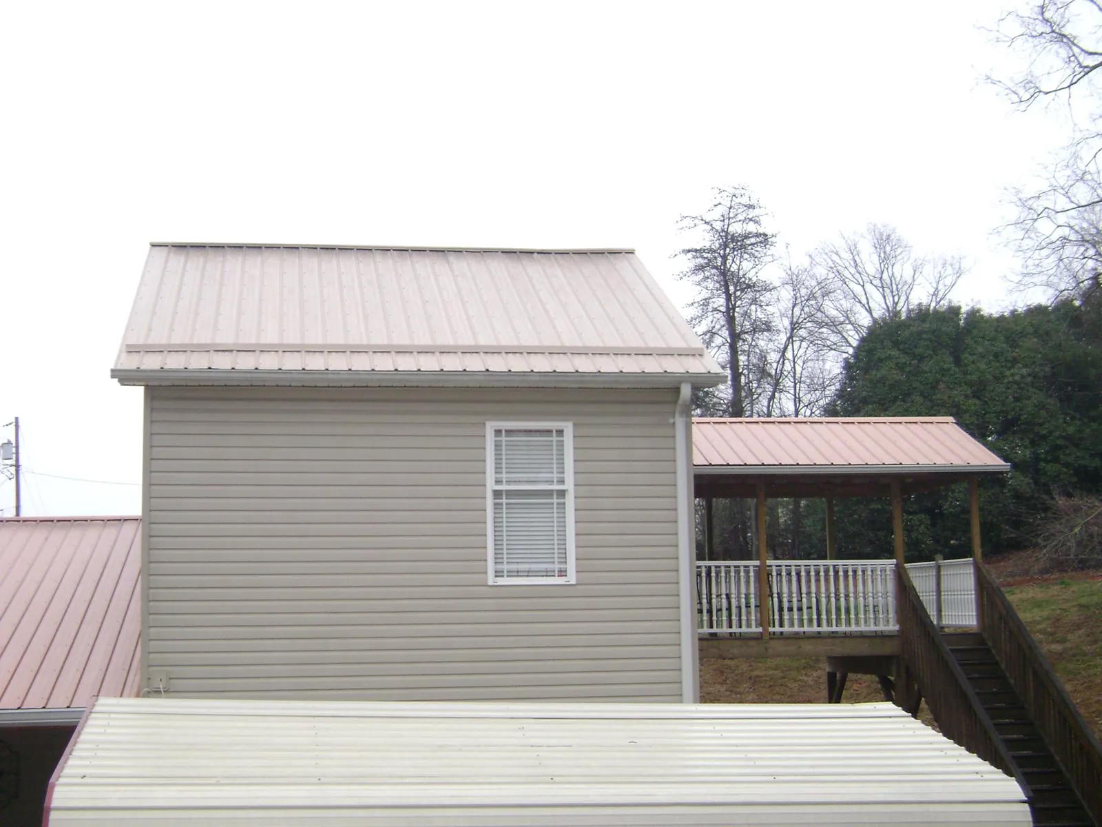Tan metal roofs on a two story addition and attached porch, from a Roof Replacement job in Pantego
