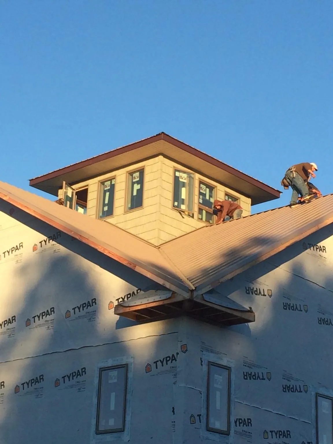 Roofers working around a rooftop cupola on a new metal roof at sunset — Roof Waterproofing in Pantego by Roofing Brothers